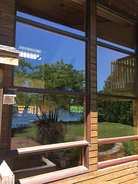 Clean cottage windows reflecting the lake and surrounding trees